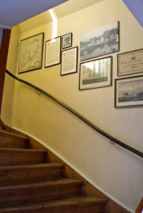 Tangga ke lantai dua yang penuh dengan peta dan foto tua